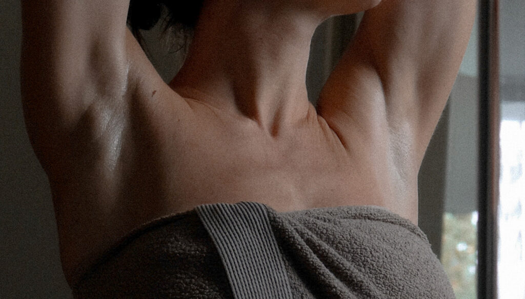 Kvinde iført håndklæde med armene over hovedet med bare armhuler