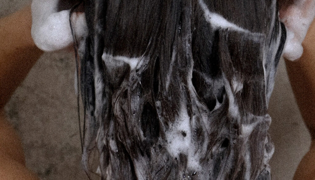 Close-up af vådt hår med shampoo i